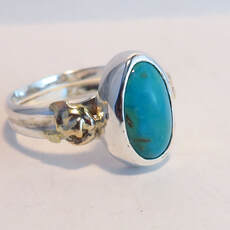  Handmade sterling silver ring with oval-shaped turquoise cabochon and gold accents on shank